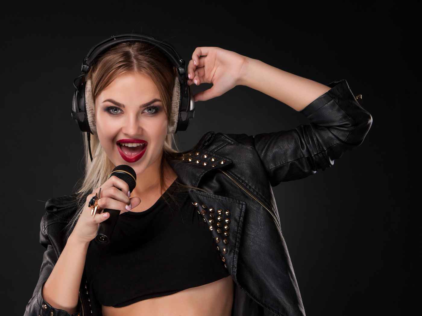 Девушка в черной кожаной куртке поет в микрофон