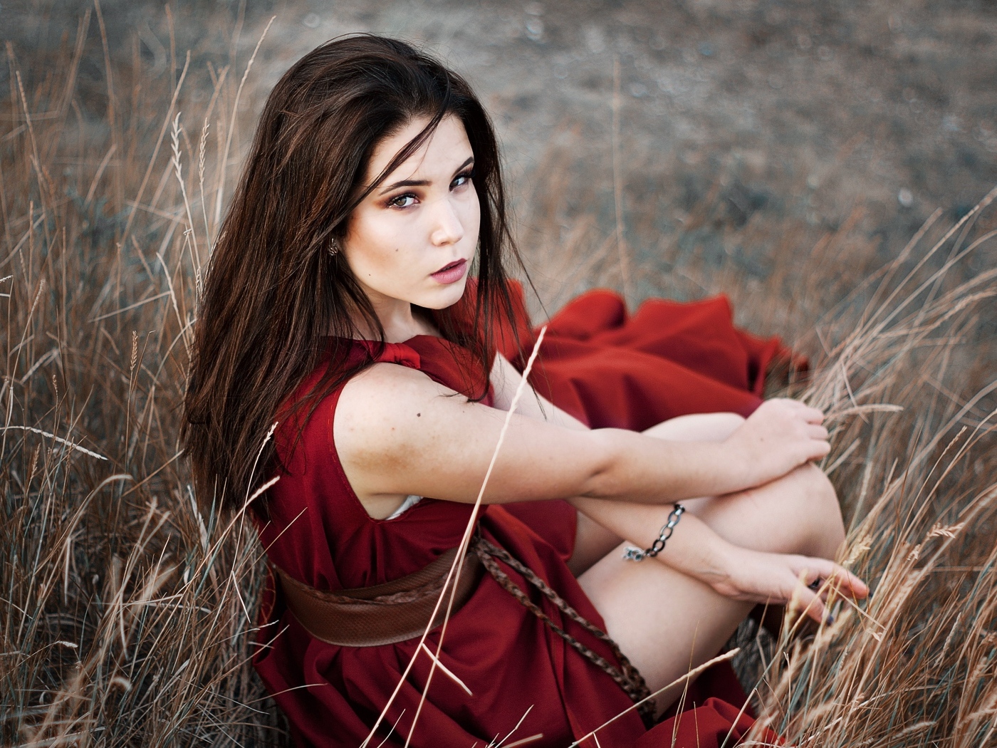 Девушка в красном платье сидит в траве