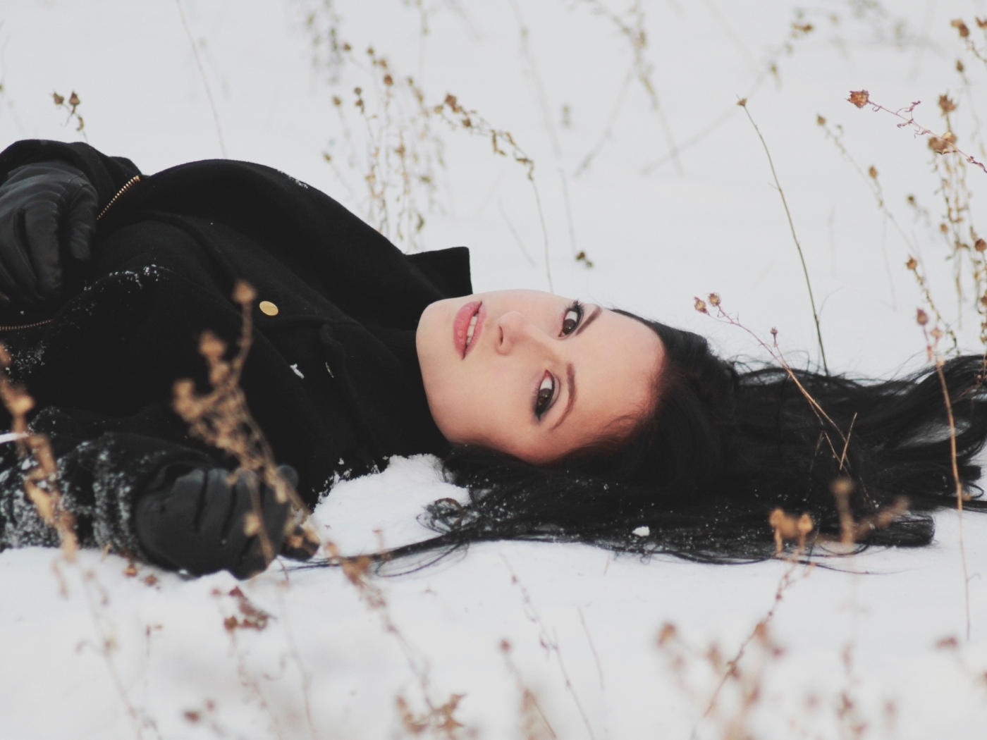 Красивая брюнетка лежит на холодном снегу