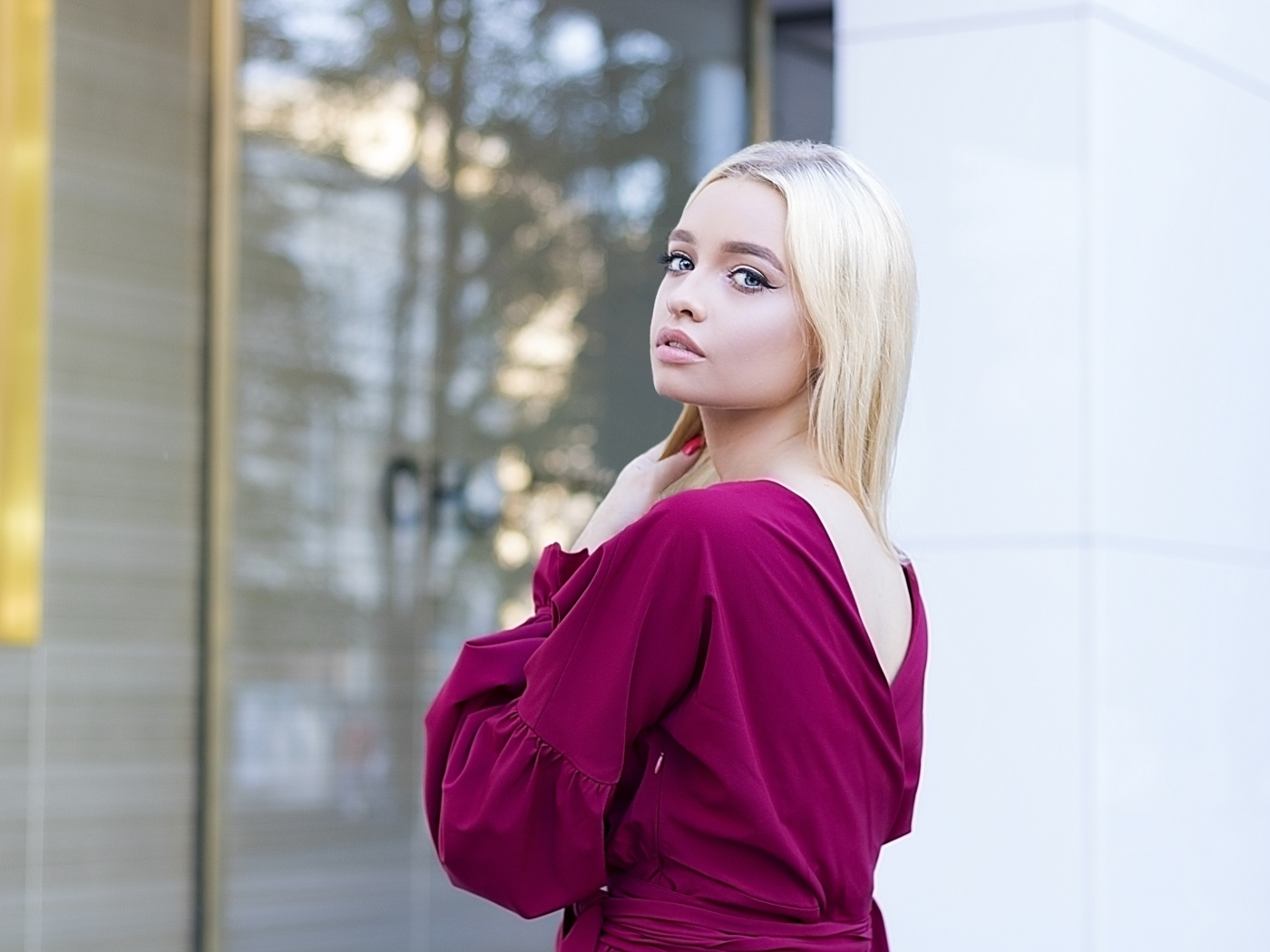 Милая девушка блондинка в платье стоит у здания