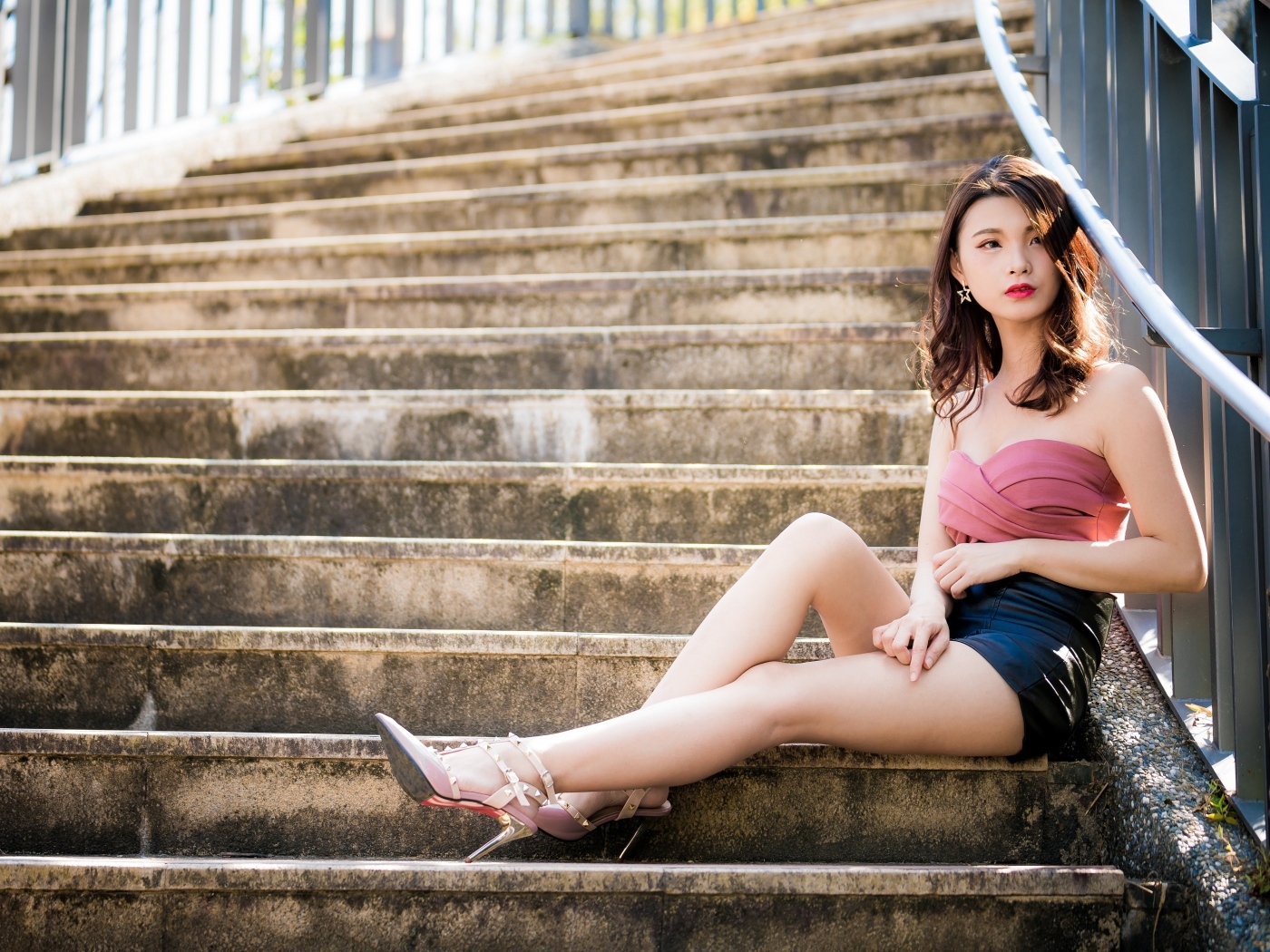 Милая стройная девушка азиатка сидит на ступеньках