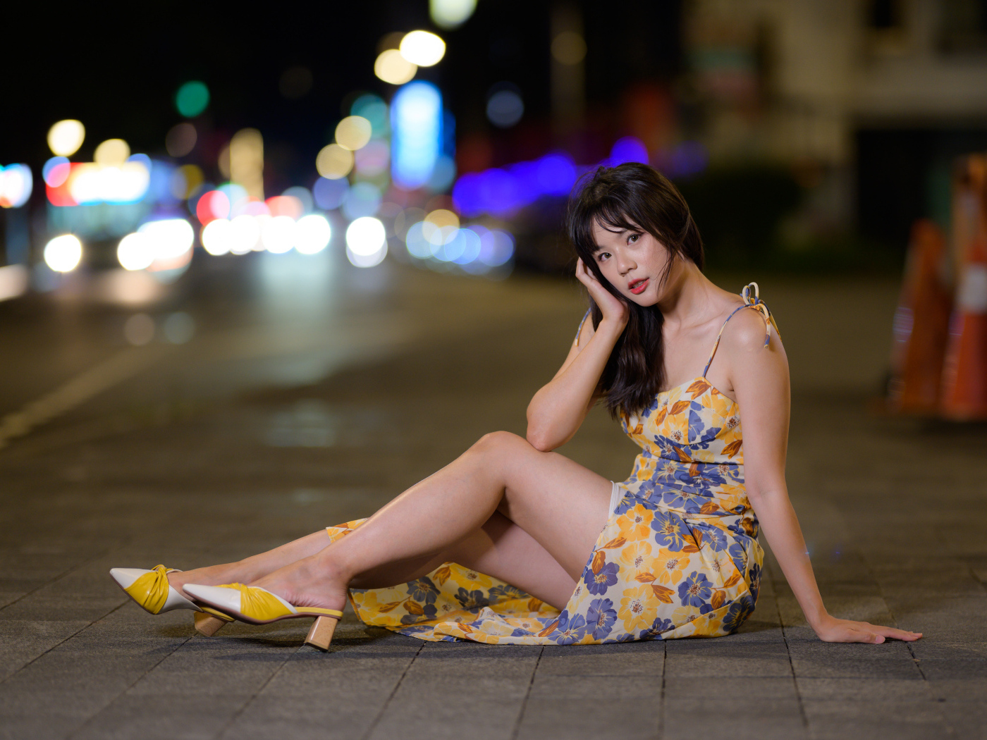 Милая нежная азиатка в платье сидит на дороге