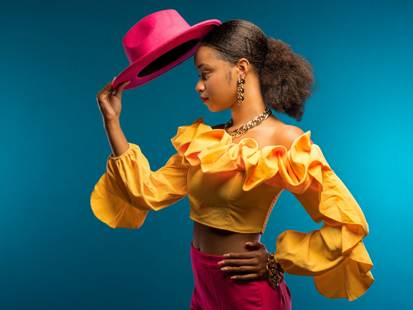 Темнокожая девушка в костюме с красной шляпой в руке