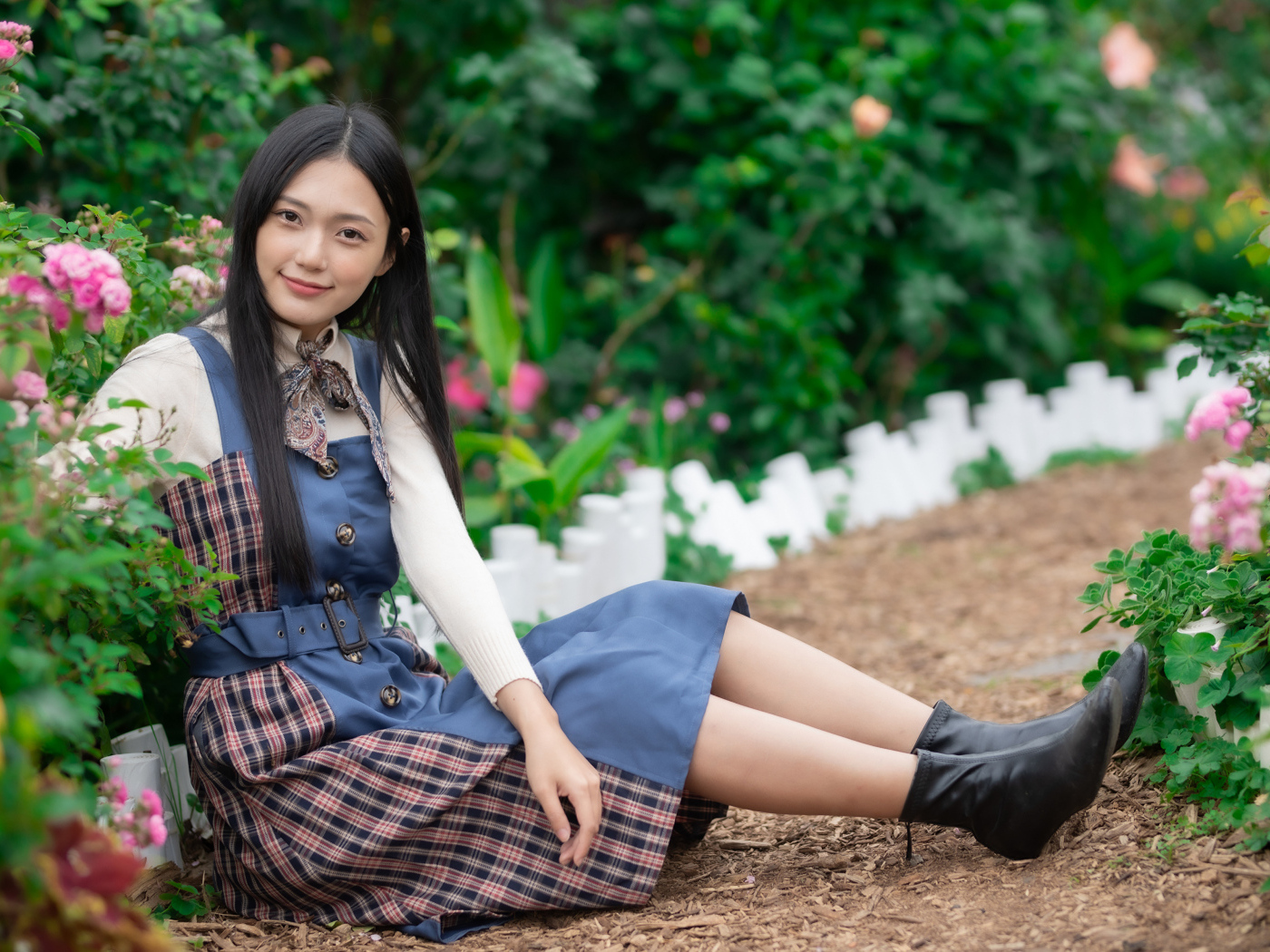 Настоящая молодая азиатка сидит на земле у клумбы