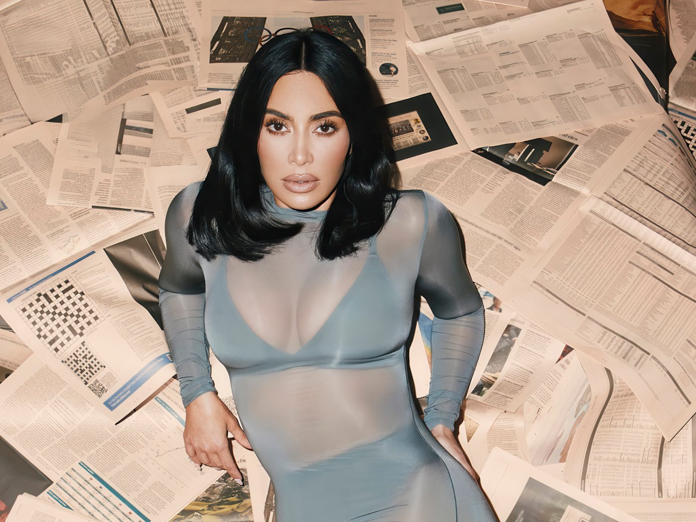 Модель Ким Кардашьян лежит на полу на газетах