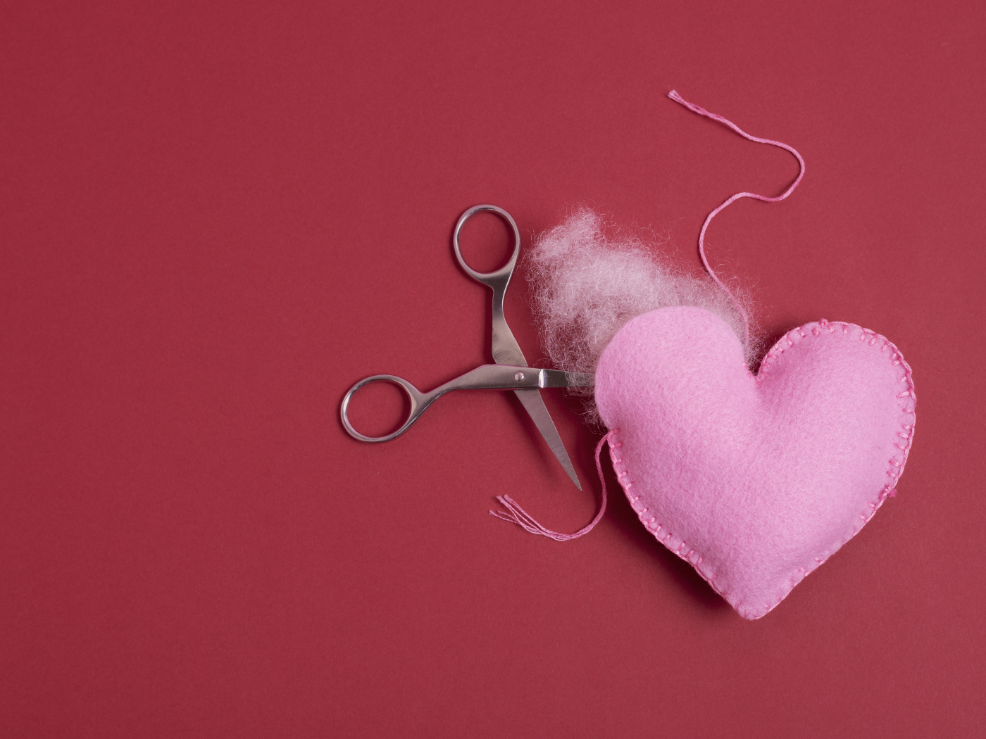 Розовое  сердце с ножницами на красном фоне