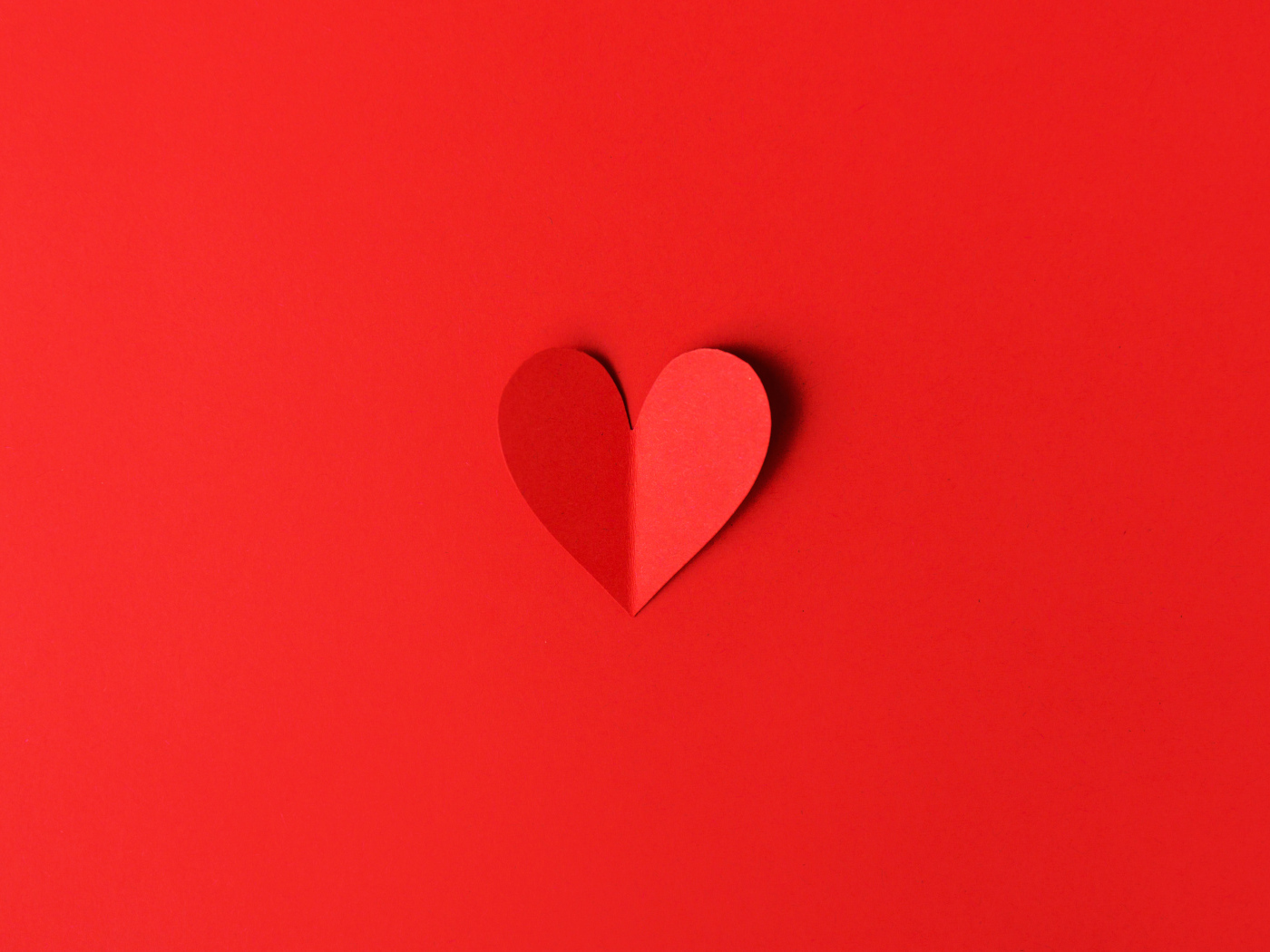 Маленькое бумажное сердце на красном фоне