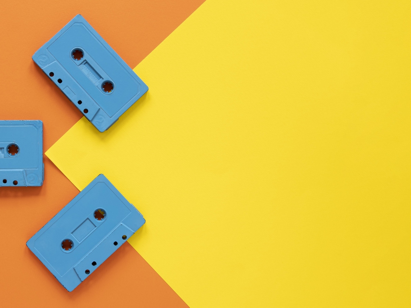 Три голубые кассеты на желто-оранжевом фоне
