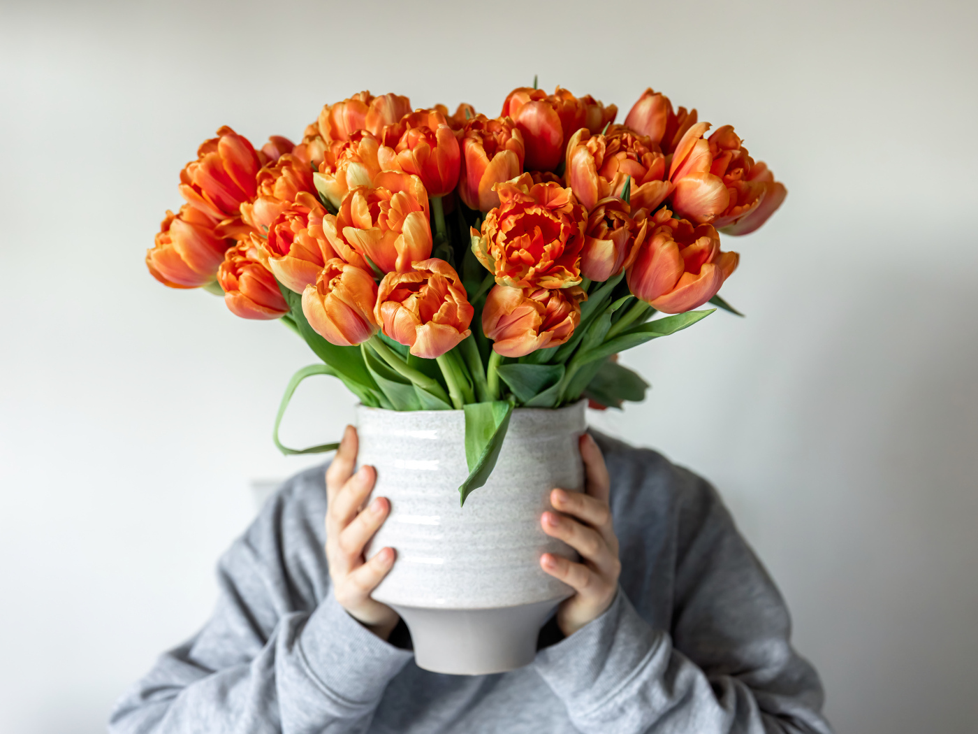 Букет оранжевых тюльпанов в вазе в руках