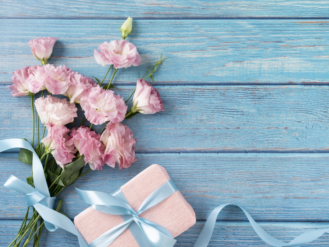 Букет розовой эустомы с подарком на голубом фоне