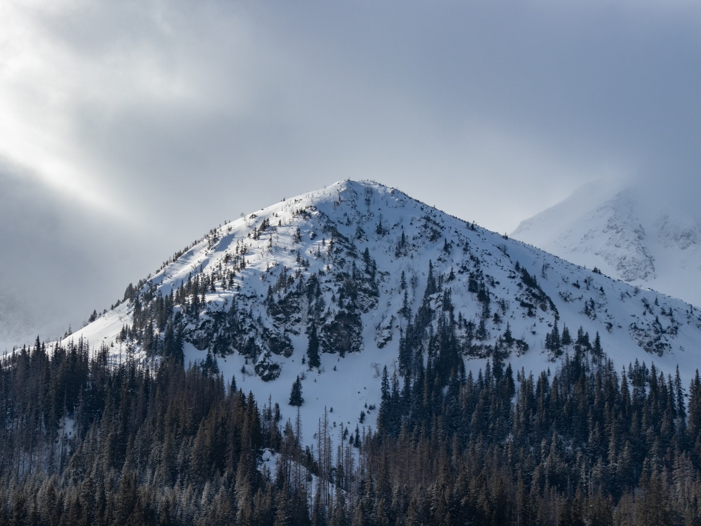 Высокая заснеженная гора под пасмурным небом