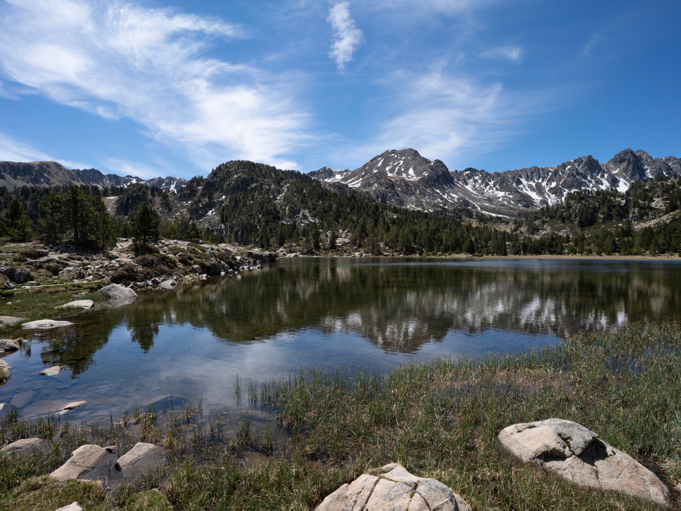 Горы отражаются в воде озера с большими камнями