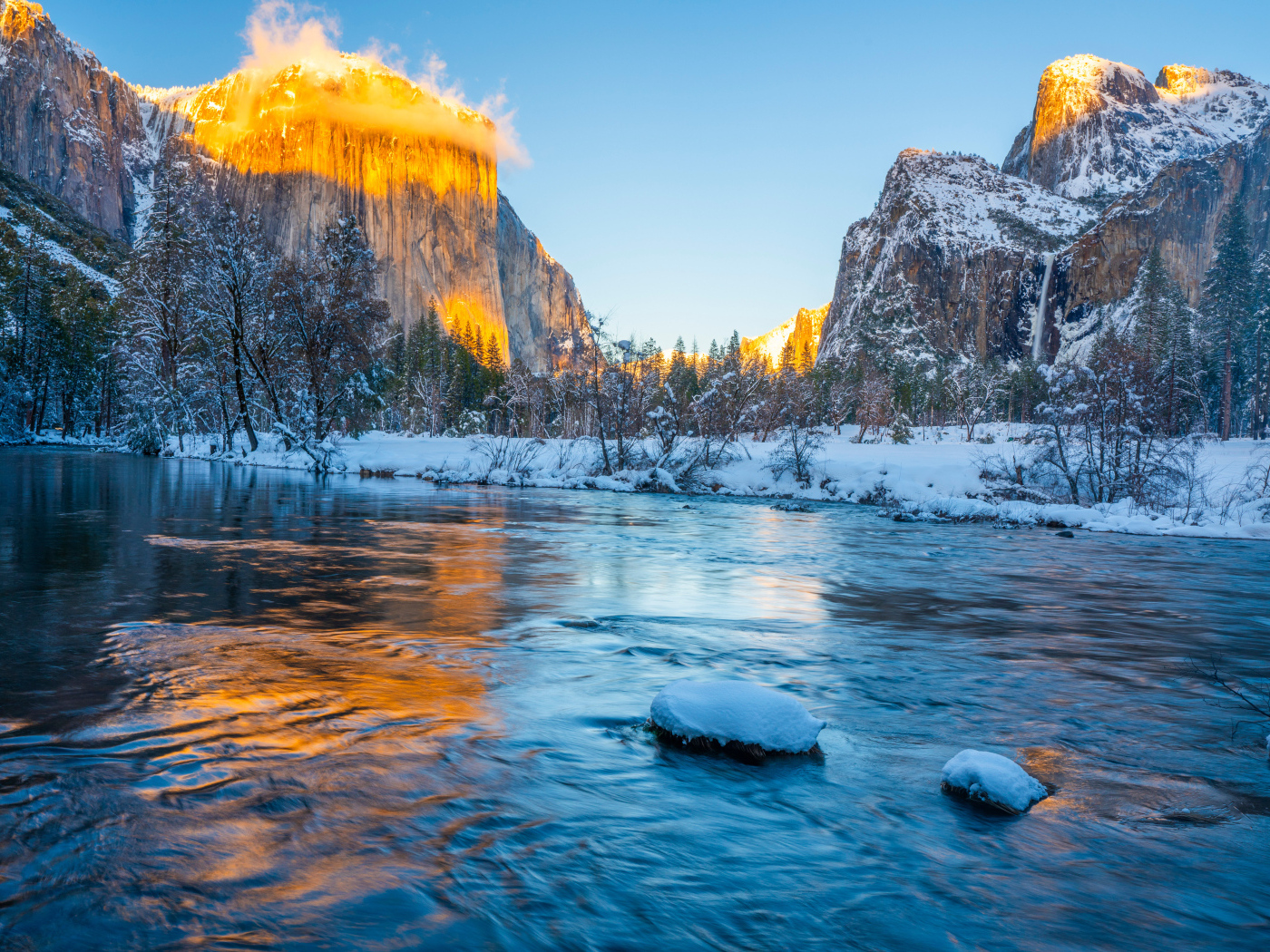 Холодная река с заснеженными берегами и горы в лучах солнца