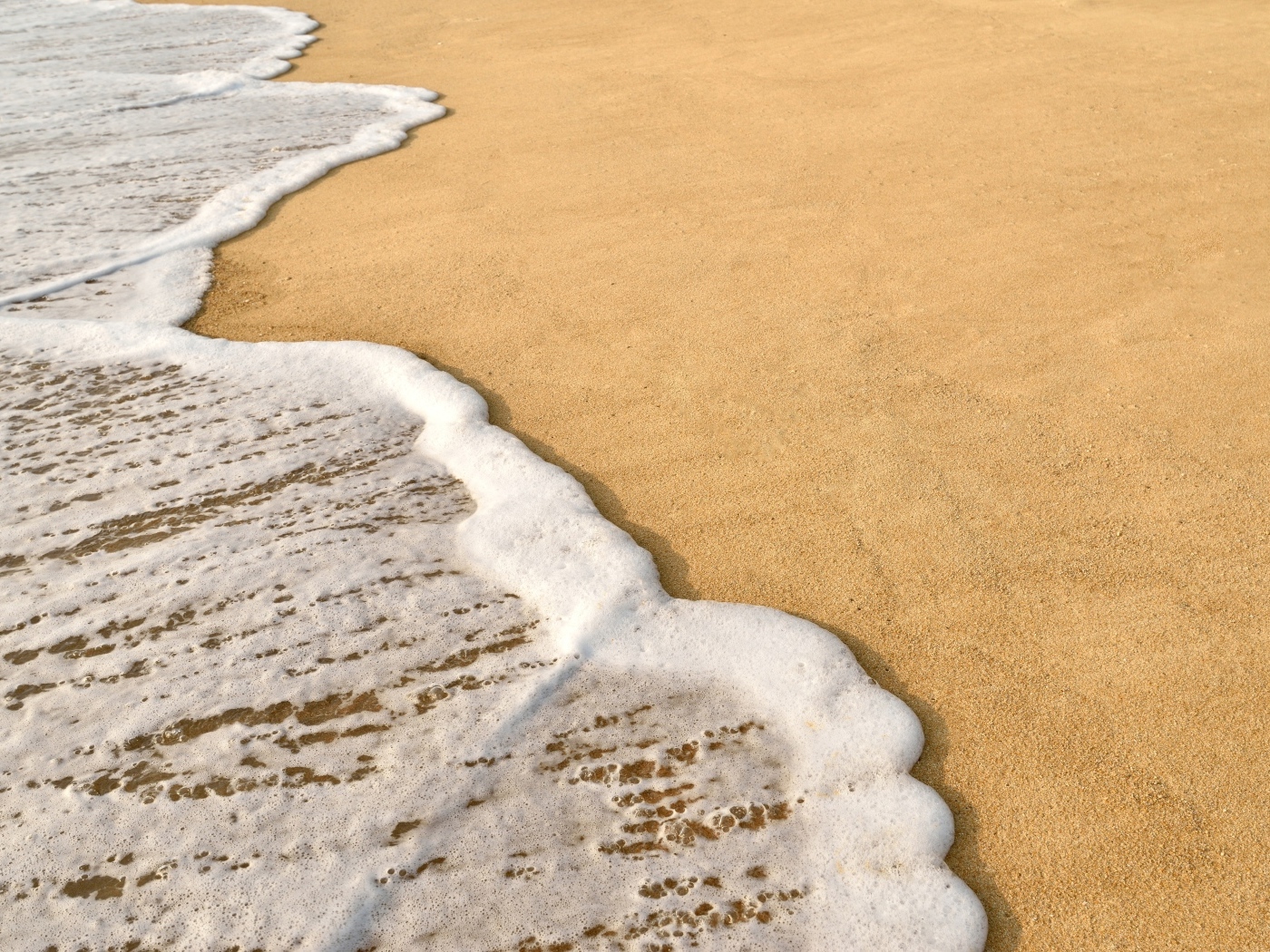 Белая пена на горячем песке на пляже