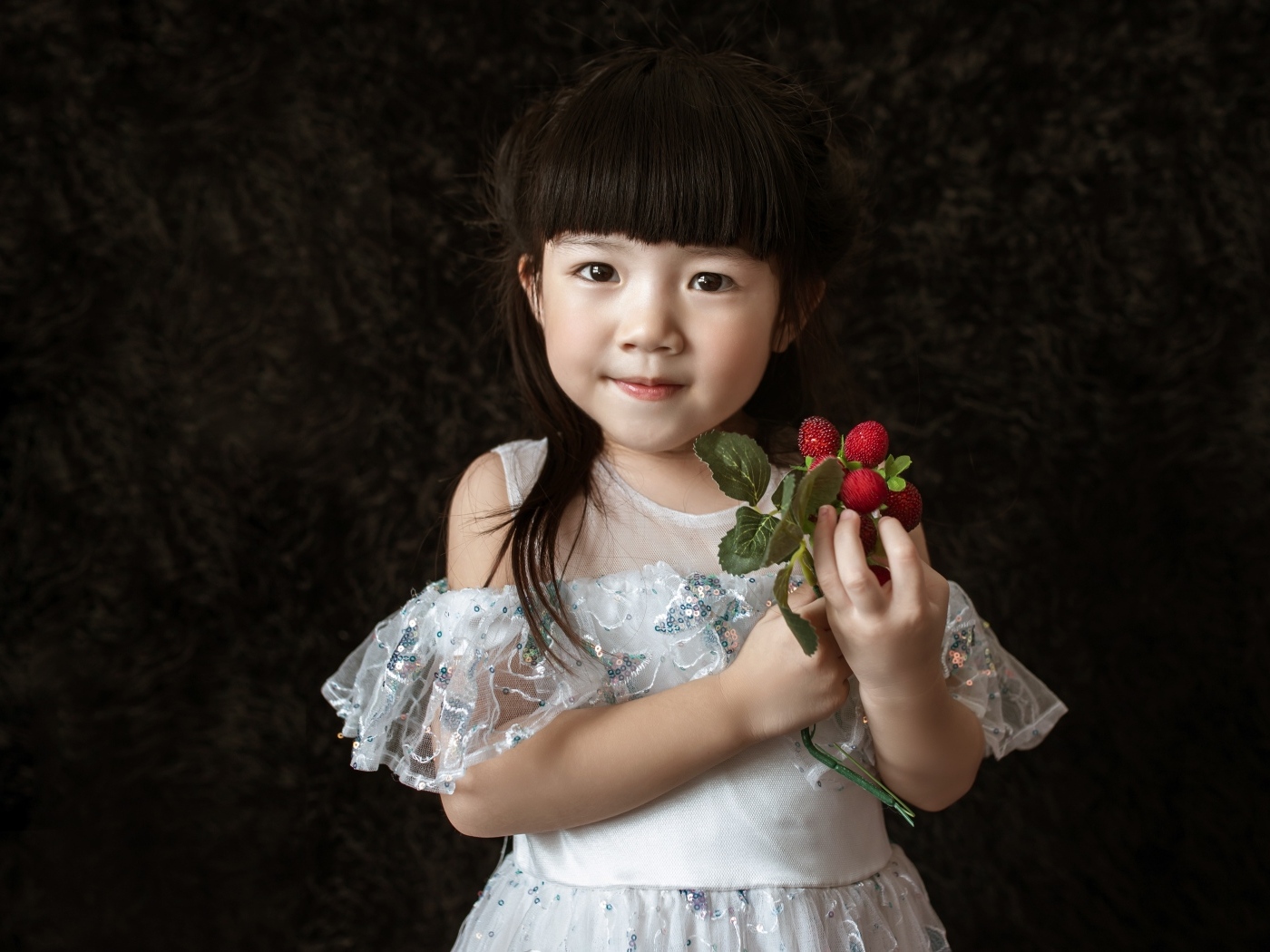 Девочка азиатка в белом платье с ягодами в руке