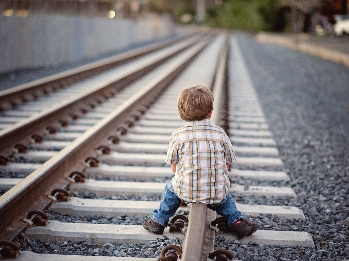 Мальчик сидит на железнодорожных рельсах