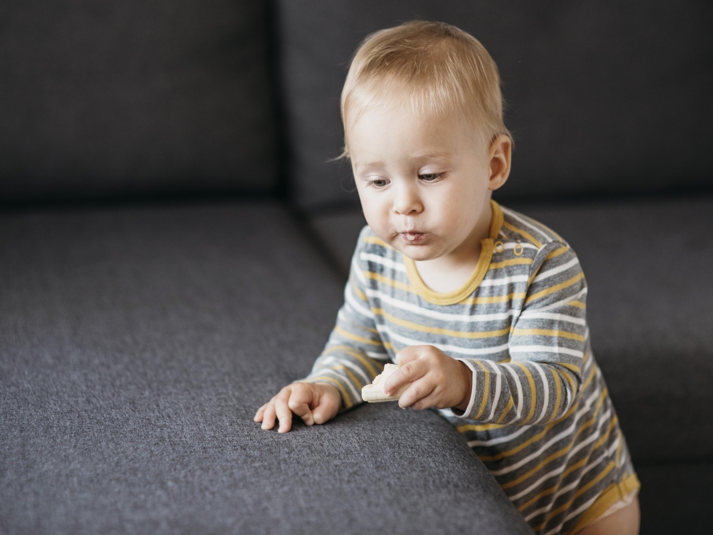 Любопытный маленький ребенок у дивана