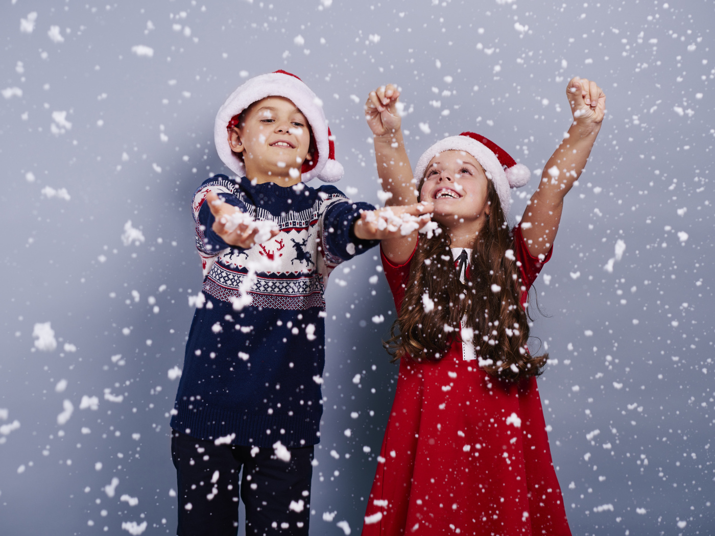 Маленькие мальчик и девочка ловят снег