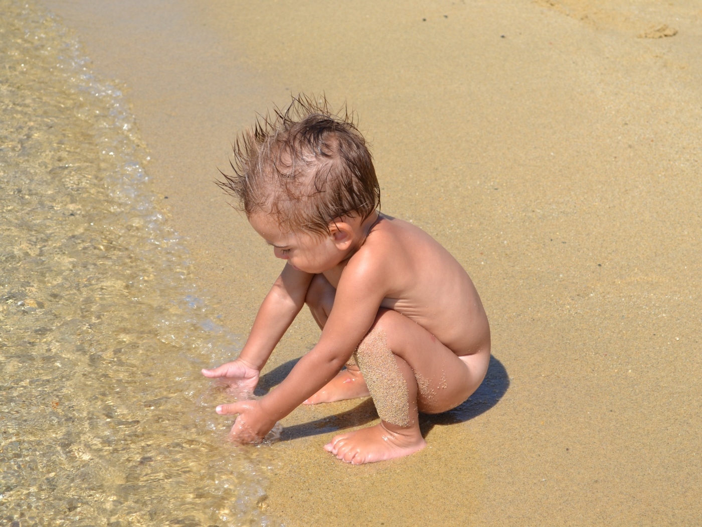 Маленький мальчик на пляже у моря на песке