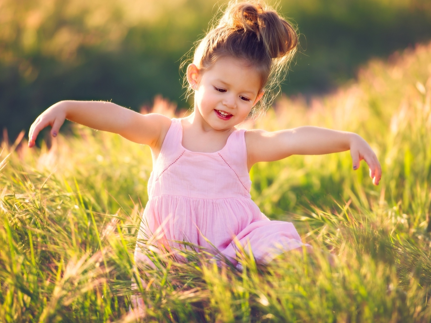 Маленькая девочка в розовом платье в зеленой траве