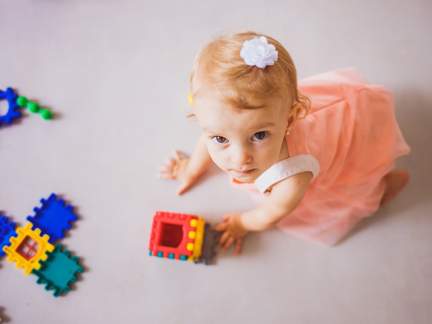 Маленькая девочка играет на полу с конструктором