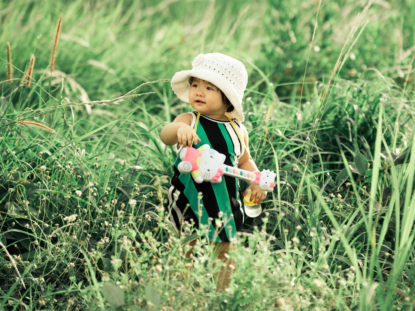 Маленькая девочка с игрушечной гитарой в траве