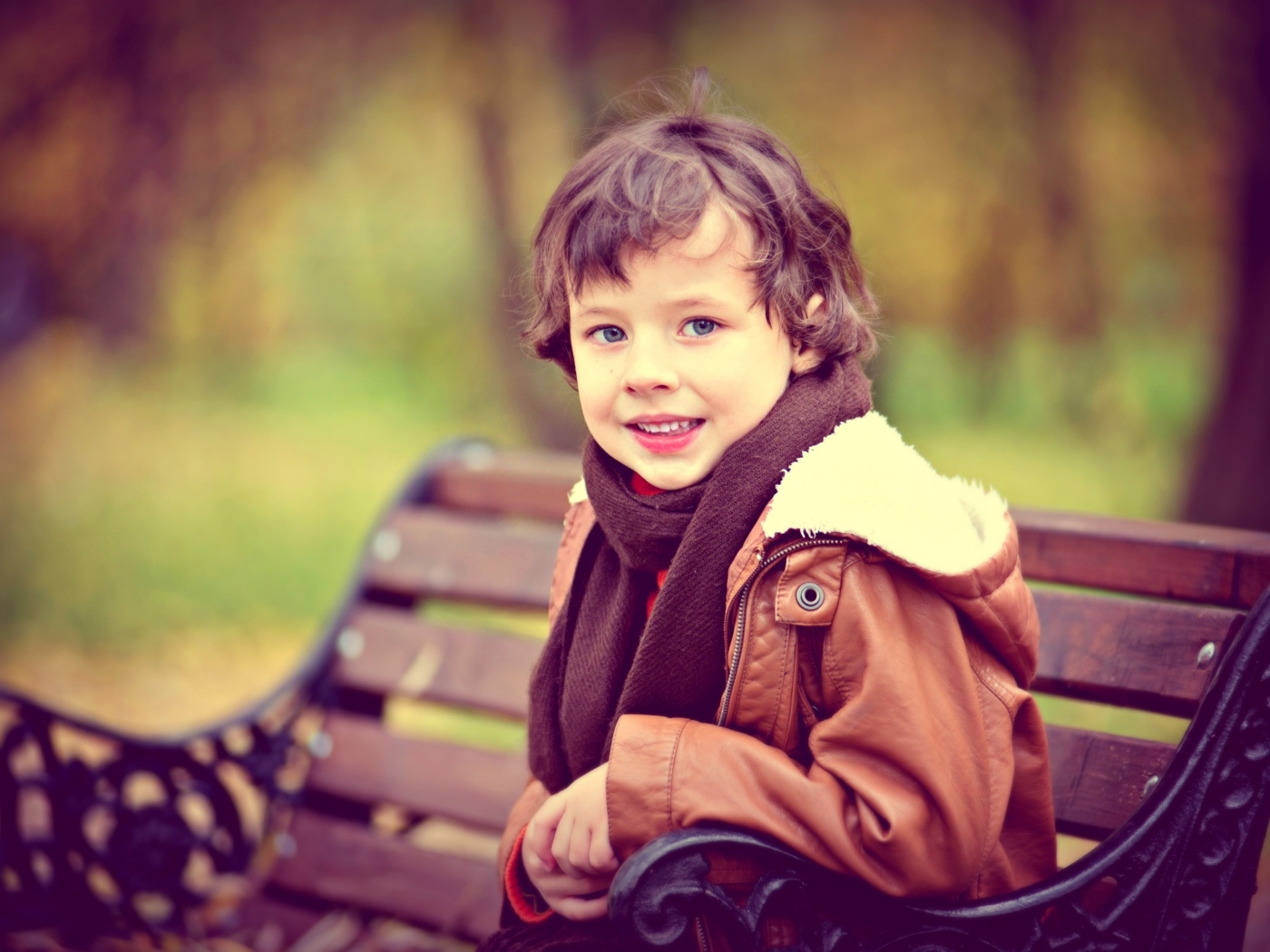 Маленький улыбающийся мальчик на лавке в парке