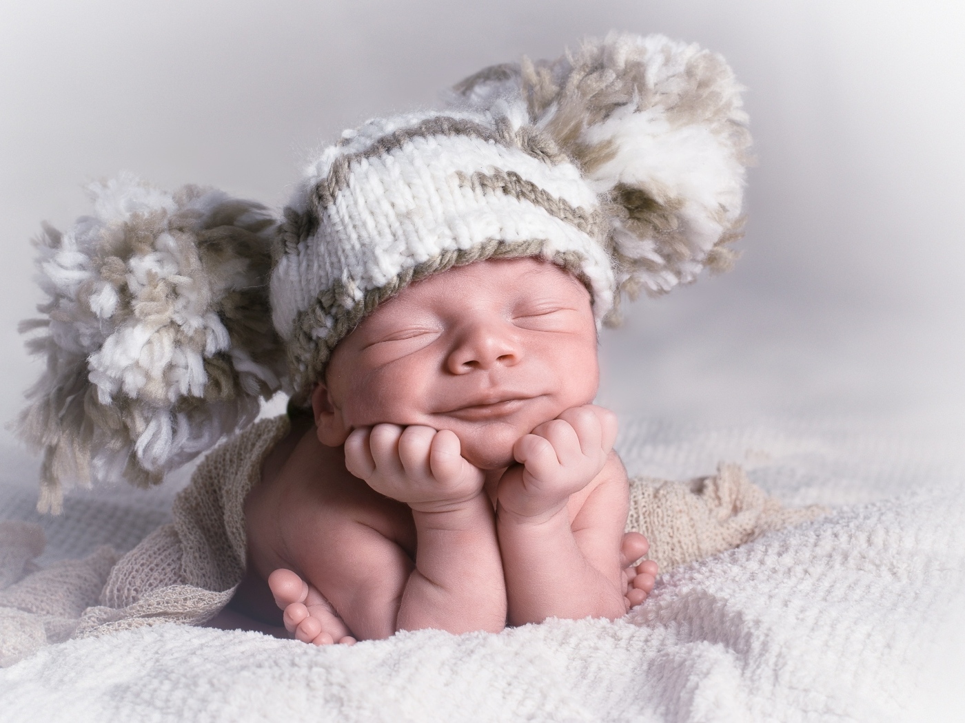 Новорожденный младенец в большой вязаной шапке