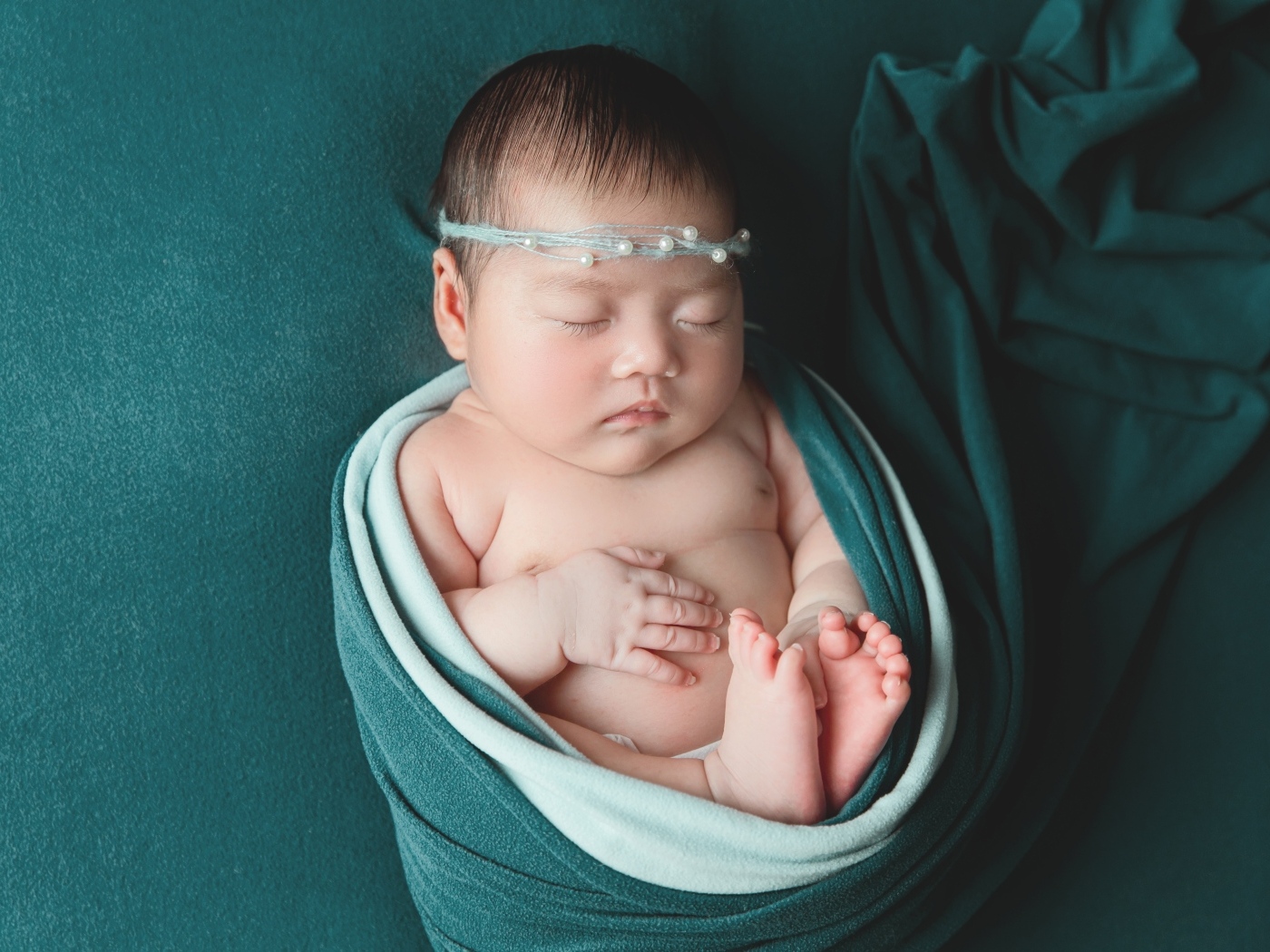 Фотография спящей новорожденной девочки на зеленом фоне