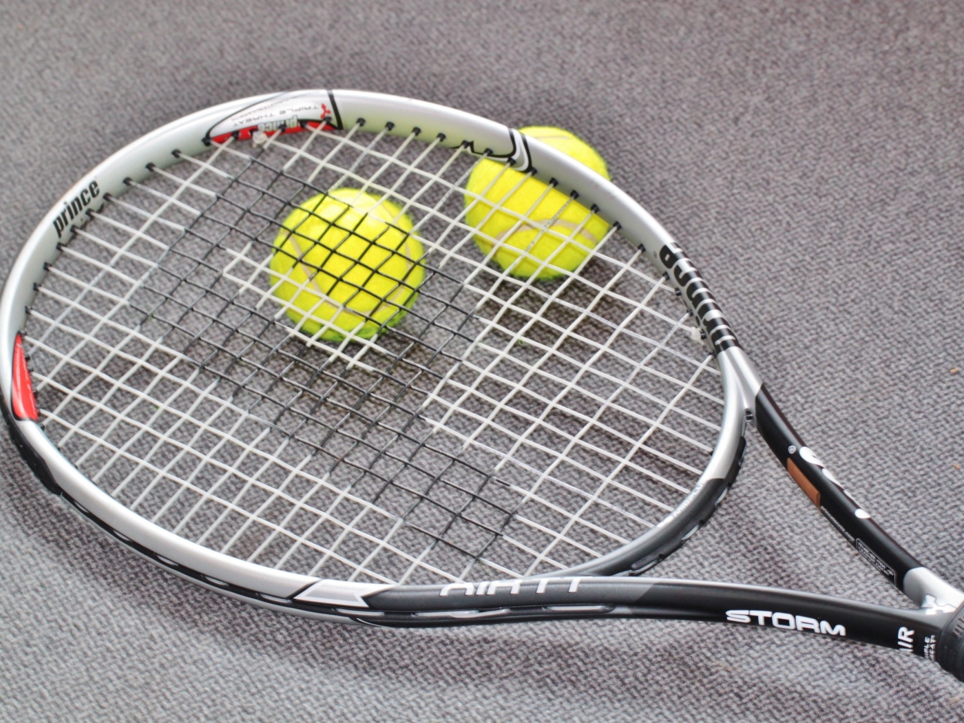 Ракетка и два мяча для тенниса на сером столе