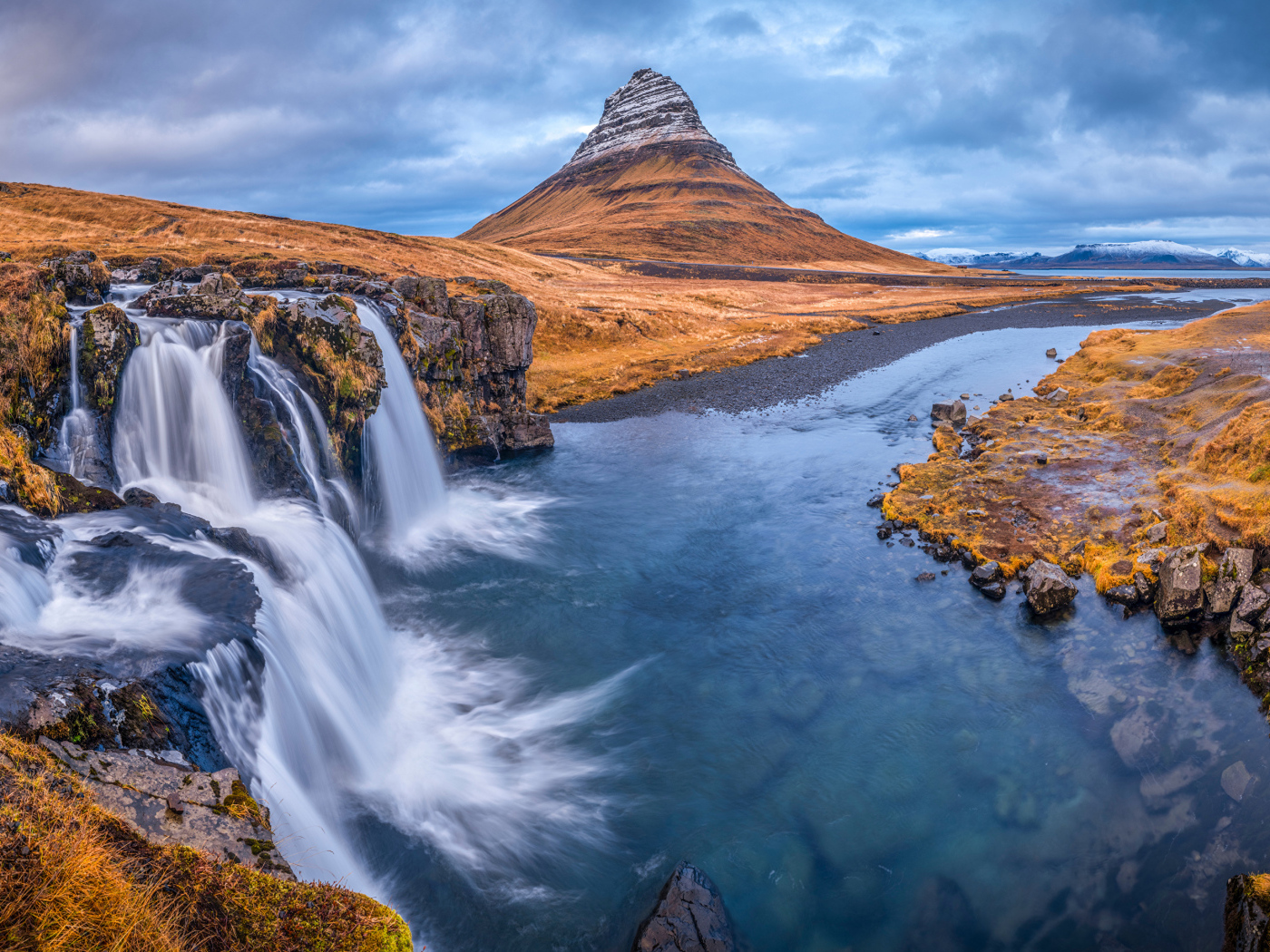 Вид на реку, водопад и гору Киркьюфетль под пасмурным небом Исладнии