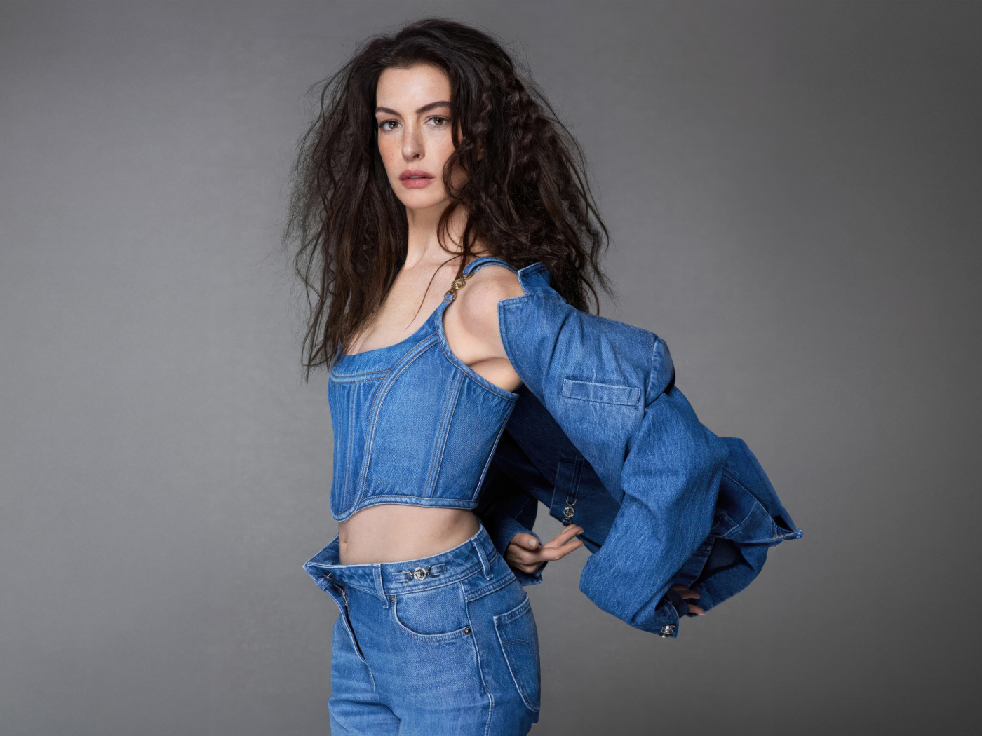 Актриса Энн Хэтэуэй в джинсовом костюме на сером фоне