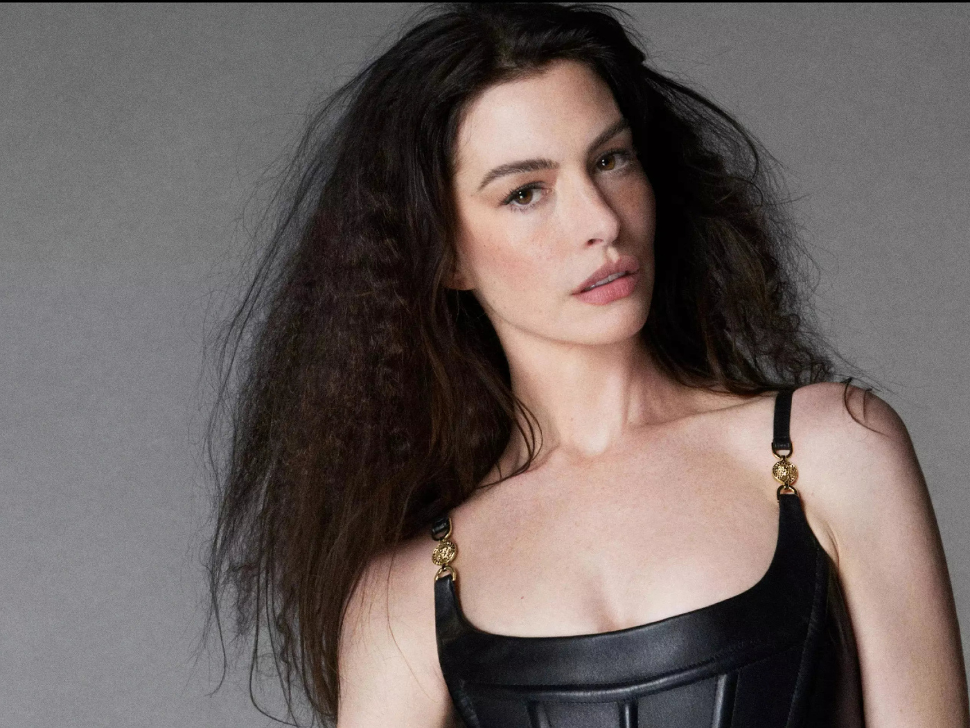 Длинноволосая актриса Энн Хэтэуэй на сером фоне