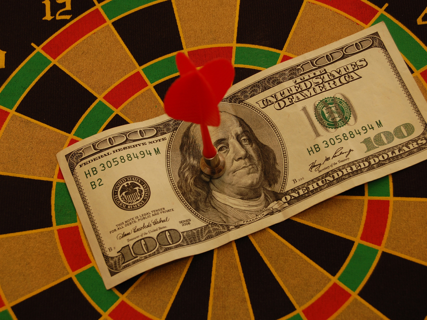 Купюра сто долларов на доске для дартс