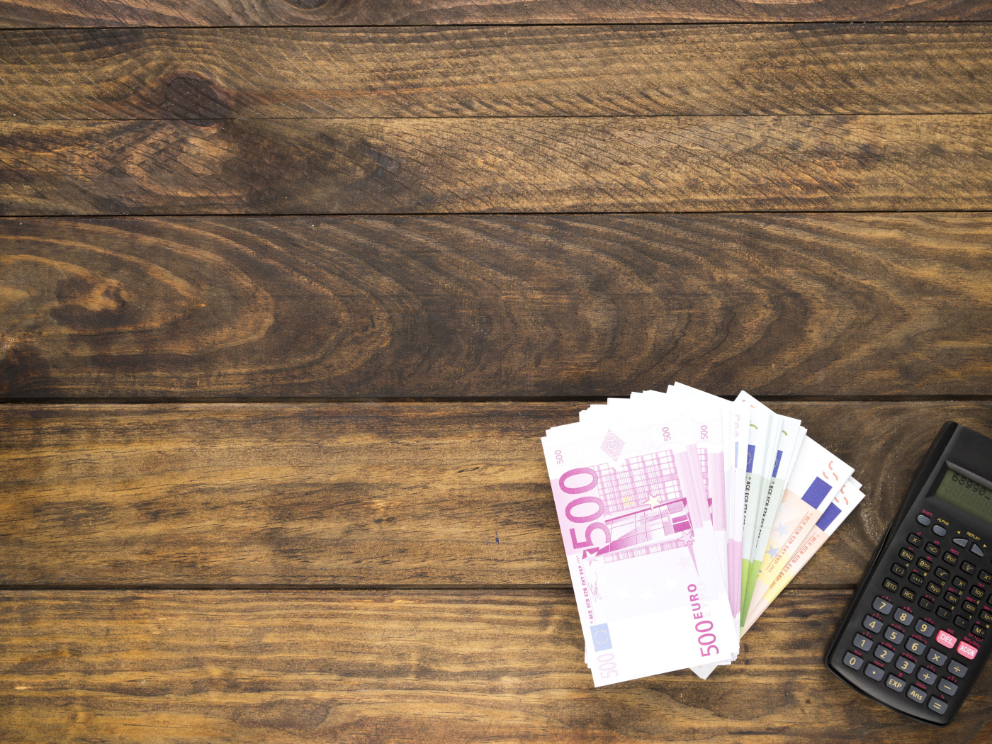 Купюры и калькулятор на деревянном фоне