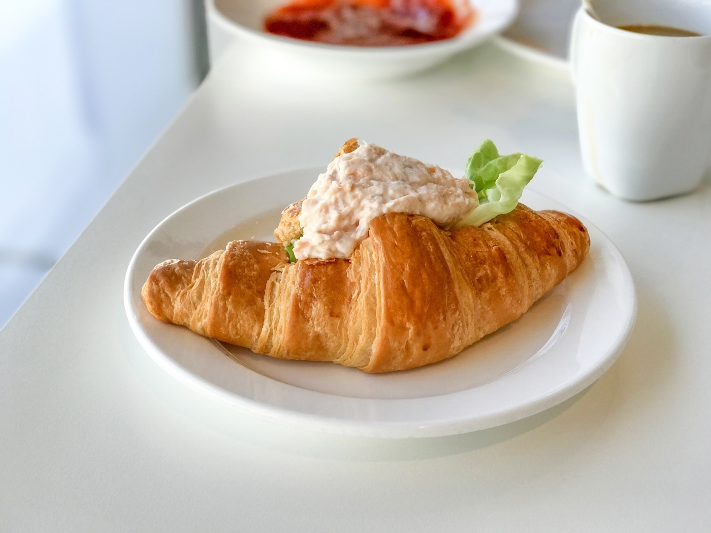Круассан с начинкой на белой тарелке на завтрак 