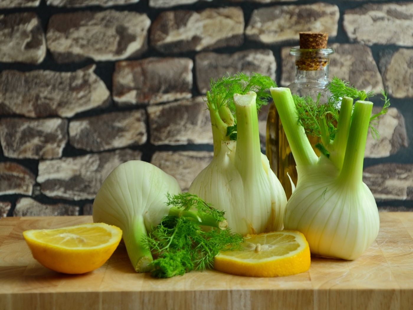 Луковицы фенхеля с кусочками лимона и маслом на столе