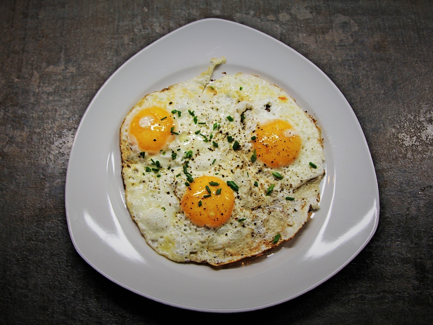 Яичница глазунья в тарелке на сером столе