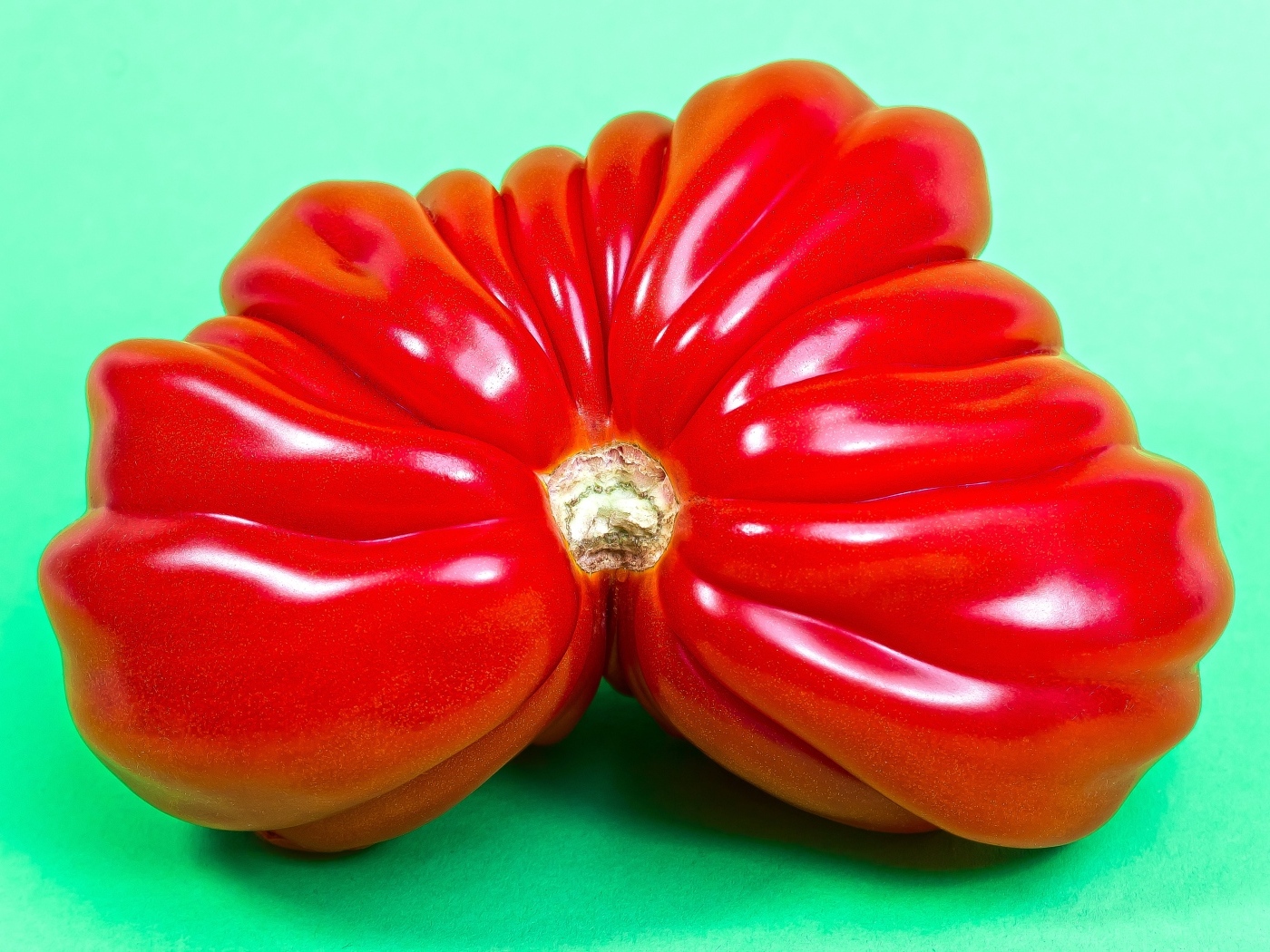 Большой спелый красный томат на зеленом фоне