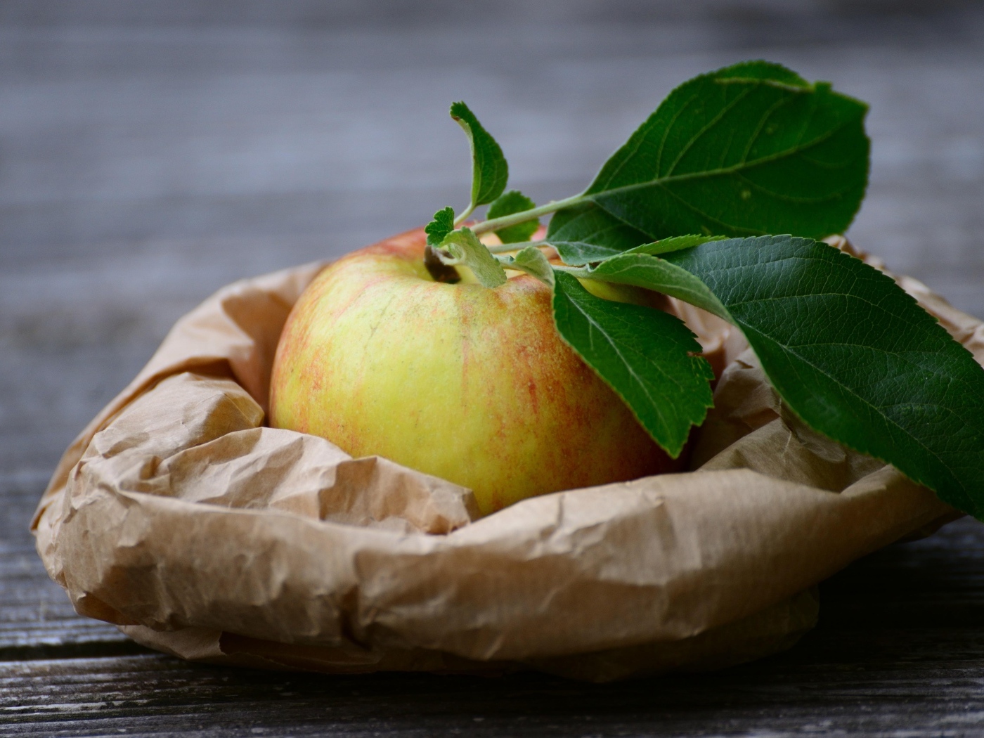 Яблоко с зелеными листьями на бумаге