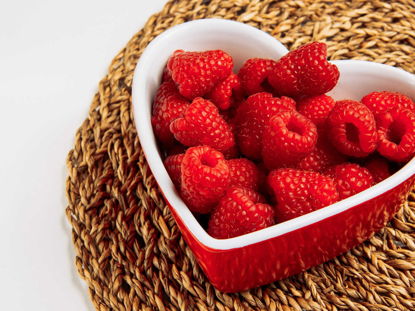 Малина в тарелке в виде сердца на столе