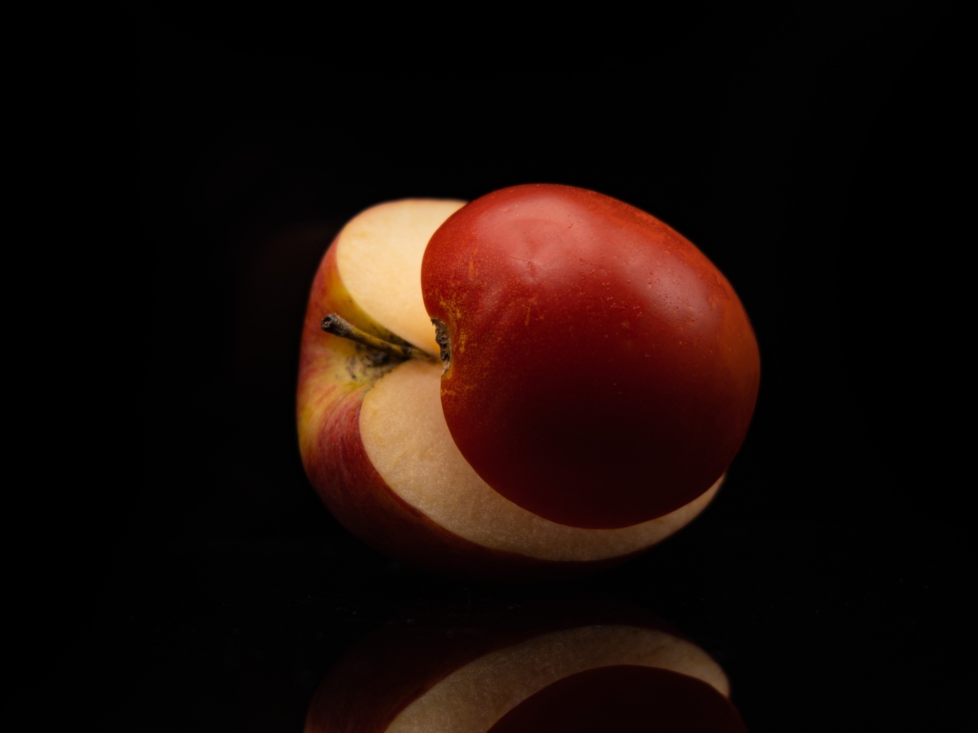 Разрезанное на половинки красное яблоко на черном фоне