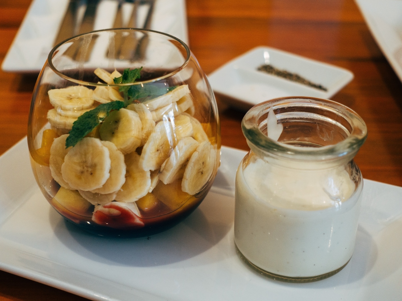 Нарезанные бананы в стакане на столе с йогуртом