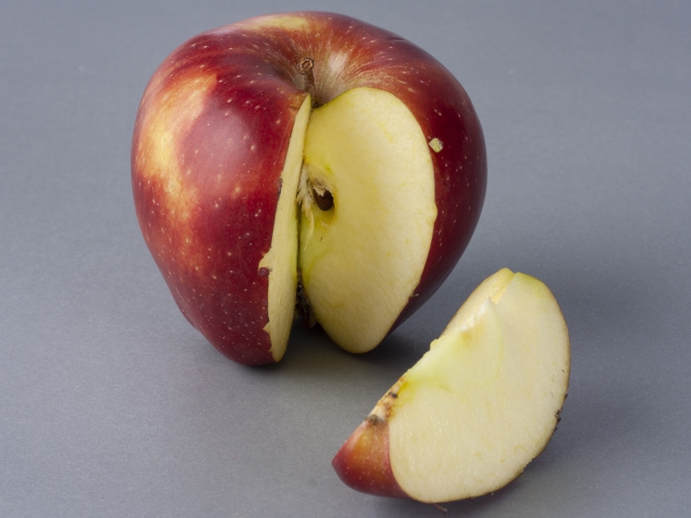 Разрезанное красное яблоко на сером фоне