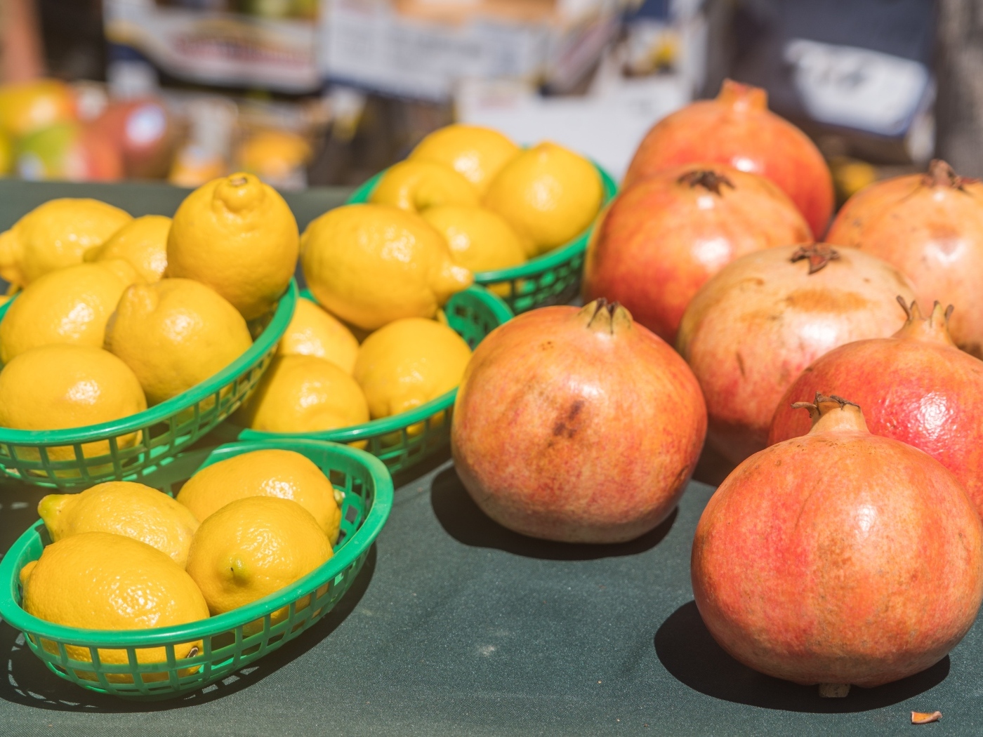 Желтые лимоны и красные плоды граната на столе