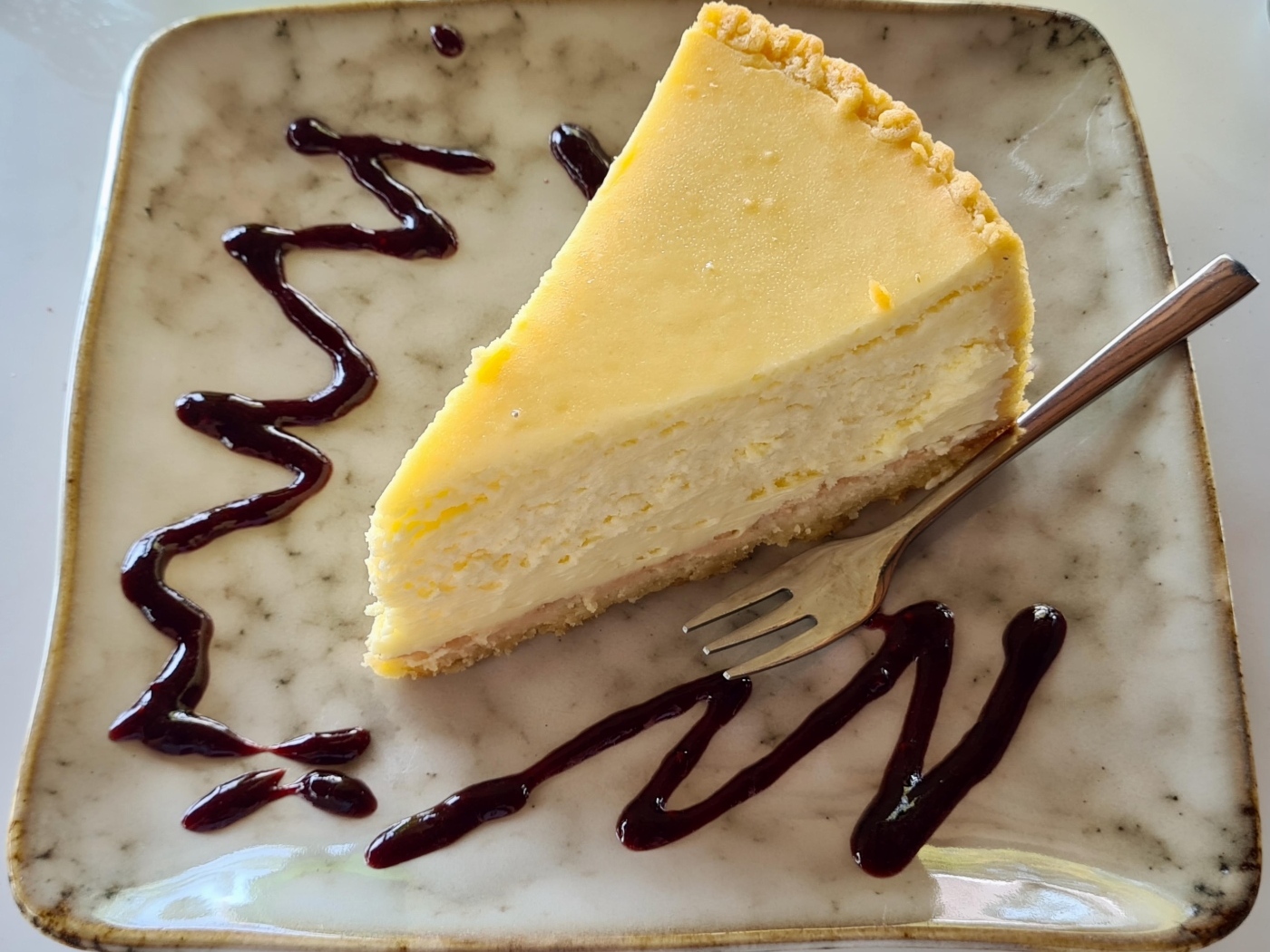 Кусок чизкейка с шоколадным топпингом на тарелке