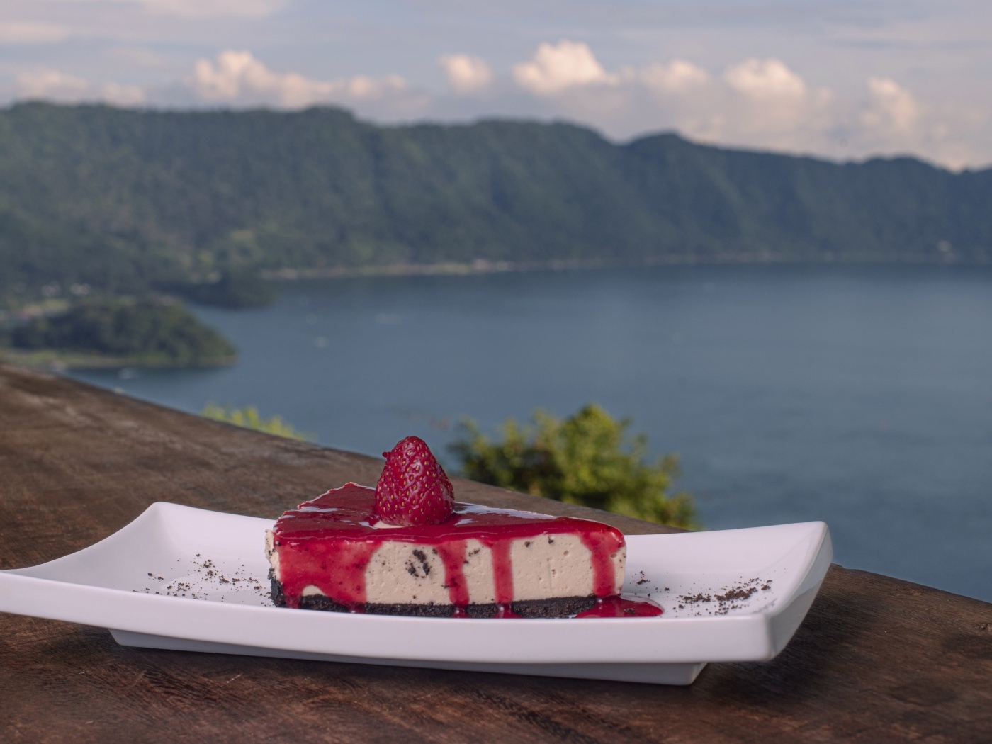 Кусок чизкейка с клубничным джемом на фоне моря