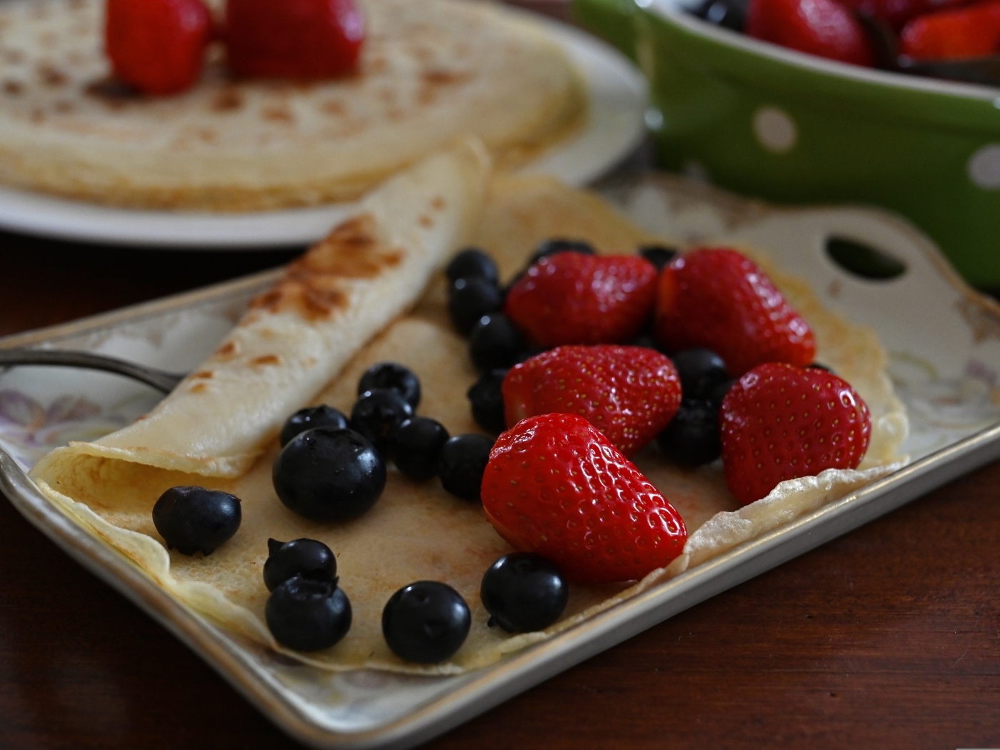 Блин с ягодами черники и клубники на тарелке