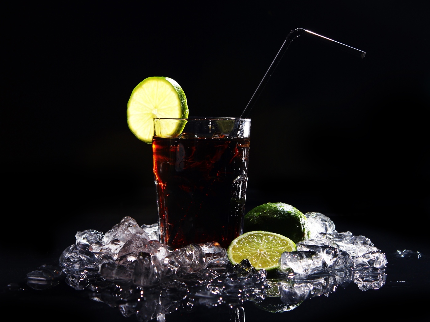 Стакан колы со льдом на черном фоне с кусочками лимона