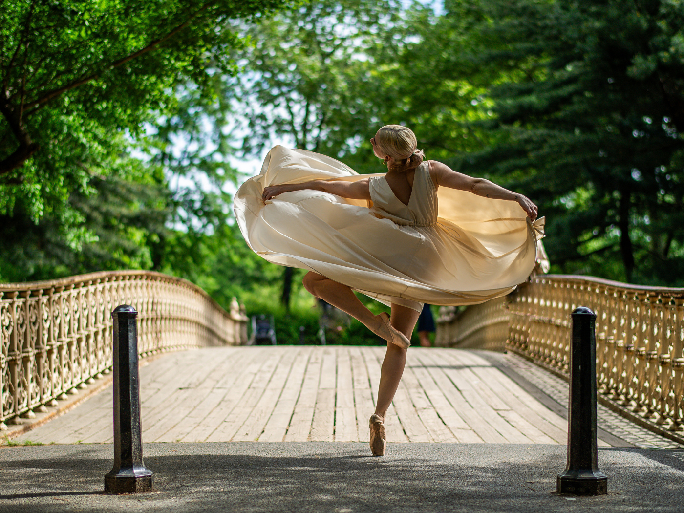 Девушка балерина в стойке на мосту